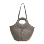 Gros plan sur la texture du cuir gris pleine fleur du sac, révélant la qualité artisanale.