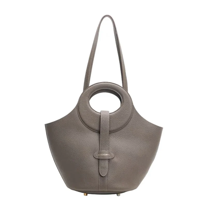 Gros plan sur la texture du cuir gris pleine fleur du sac, révélant la qualité artisanale.