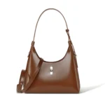 Sac à main croissant en cuir marron avec coutures apparentes.