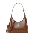 Sac à main croissant en cuir marron avec coutures apparentes.