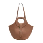 Sac en cuir marron doré posé sur une table avec des accessoires de mode, soulignant son utilisation polyvalente.
