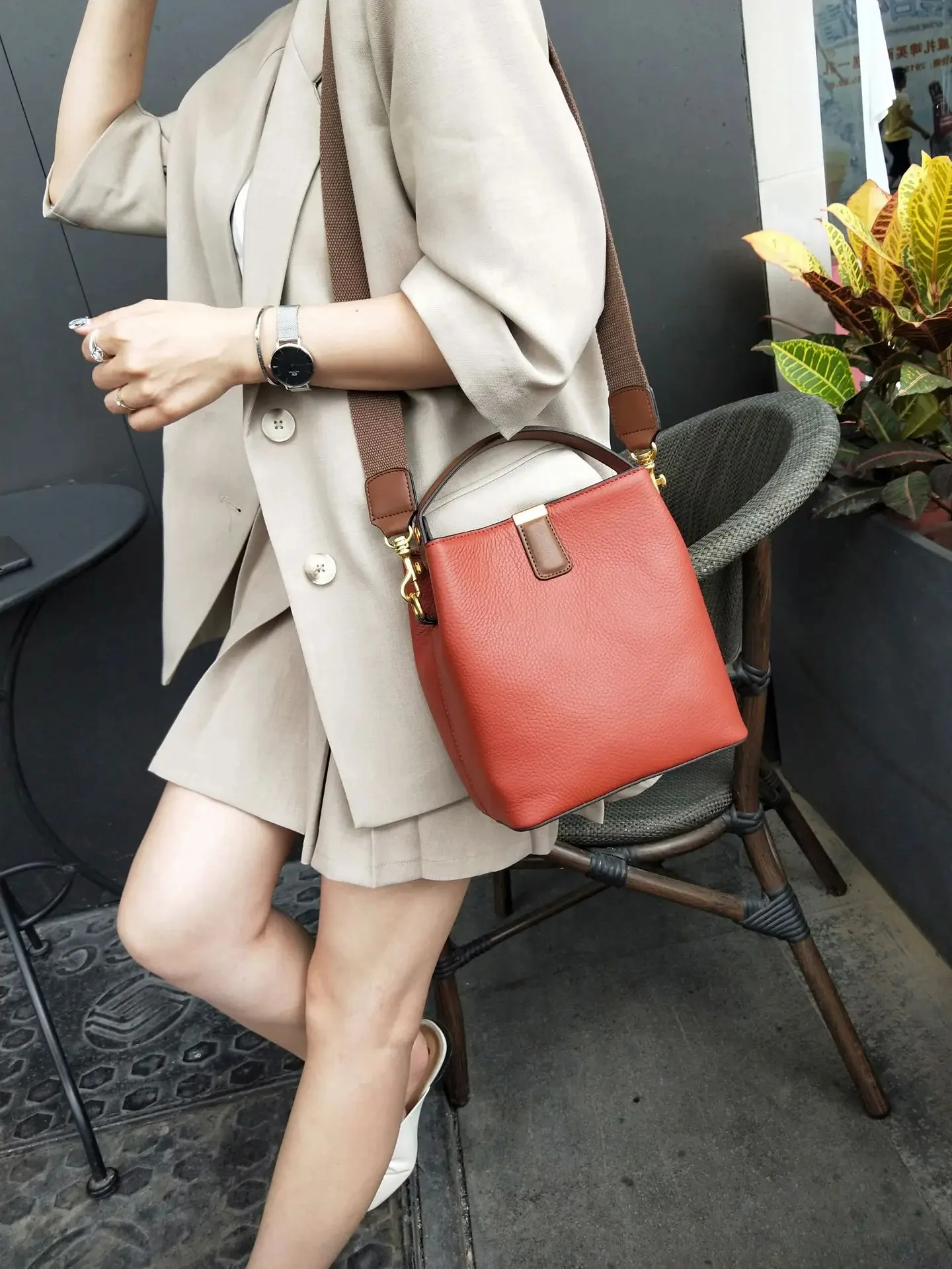 Femme portant un sac seau rouge bordeaux en cuir élégant