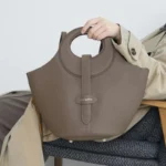 Femme portant le sac en cuir gris éléphant à l’épaule, démontrant le confort et le style décontracté du sac.