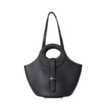 Vue de face du sac panier en cuir noir posé sur une chaise, montrant son design structuré et élégant.