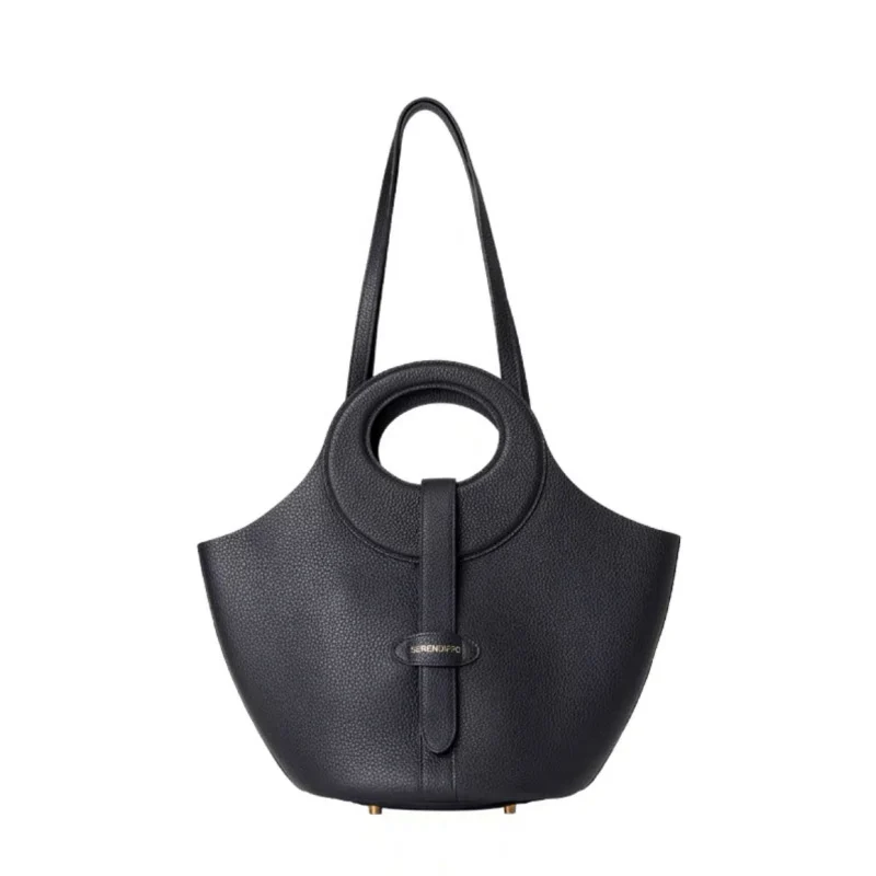 Vue de face du sac panier en cuir noir posé sur une chaise, montrant son design structuré et élégant.