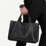 Détail des poignées ergonomiques de la sacoche cuir tressé. porté par un homme