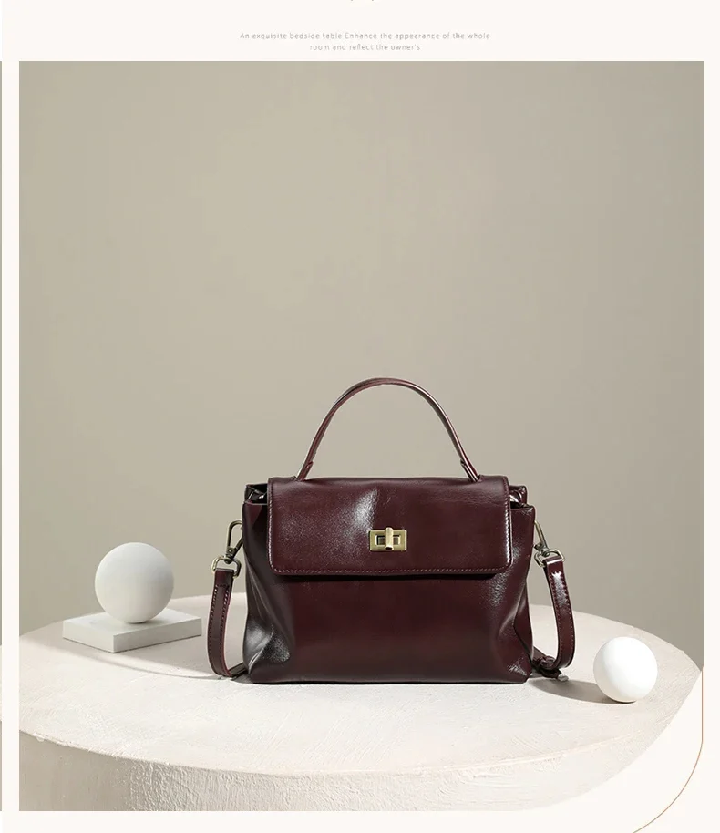 Sac à épaule femme en cuir noir posé sur une table en bois.